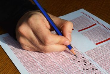 hand-with-pencil-filling-out-answers-on-exam-test-answer-sheet