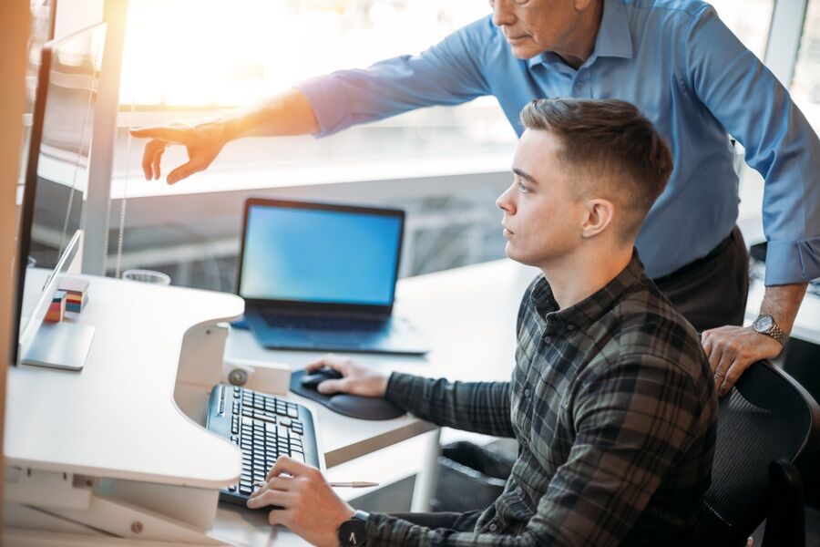 colleague-mentoring-younger-associate-in-business-office-while-pointing-at-data-on-computer-monitor